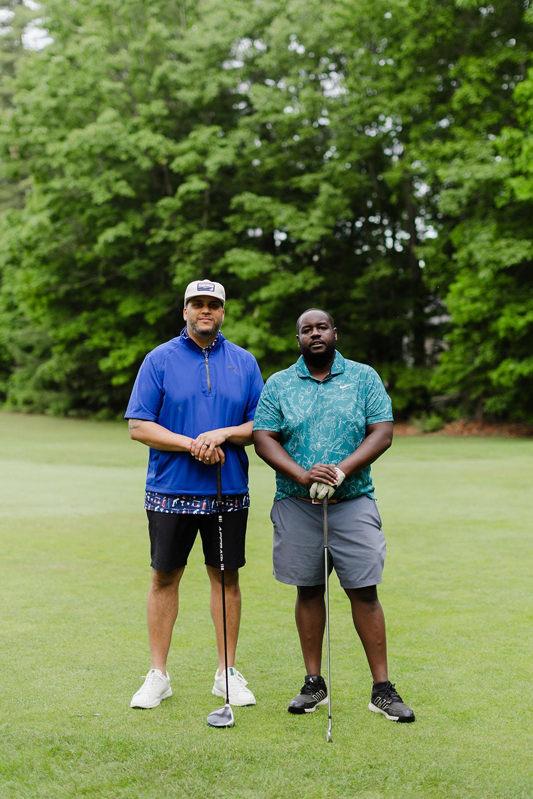 Two teammates standing with golf clubs on the green at the outing